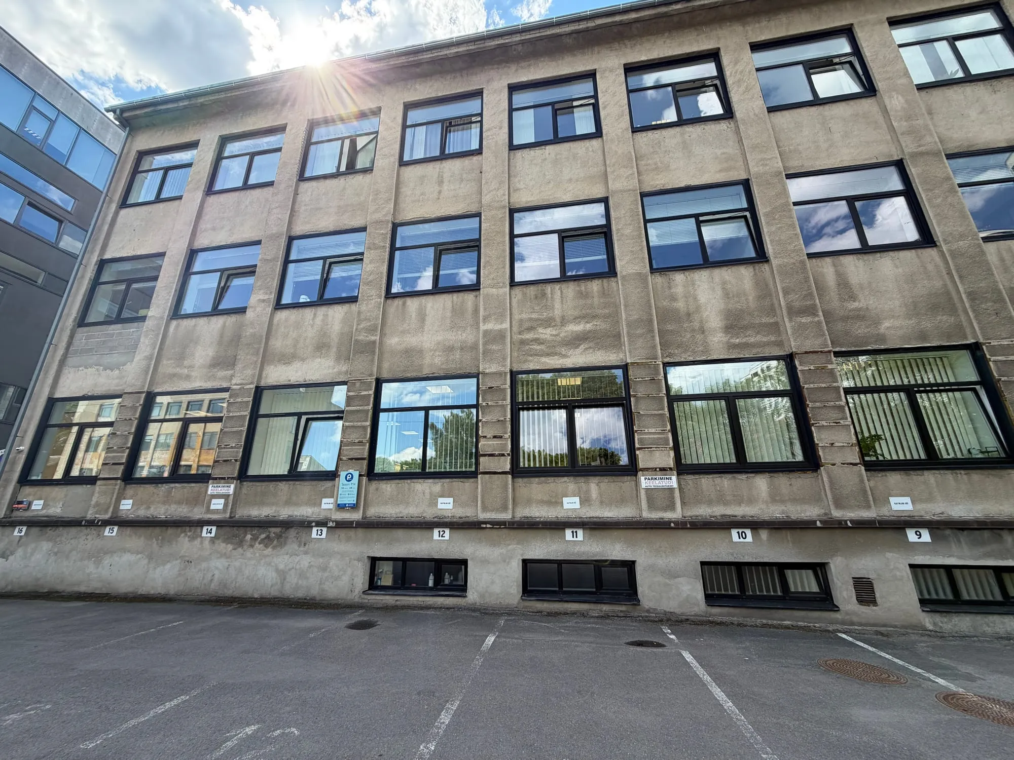 Värskelt pestud akendega vanem kontorihoone sisehoovis, taustaks sinine taevas