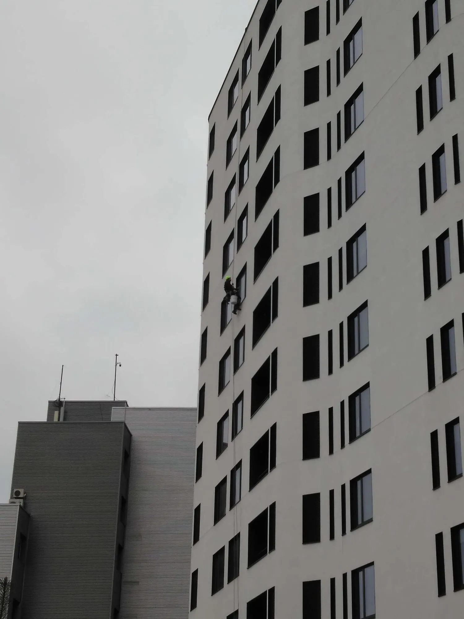 Köistehnik pesuämbriga köiel korterelamu keskkorrustel, kõrval naaberhoone