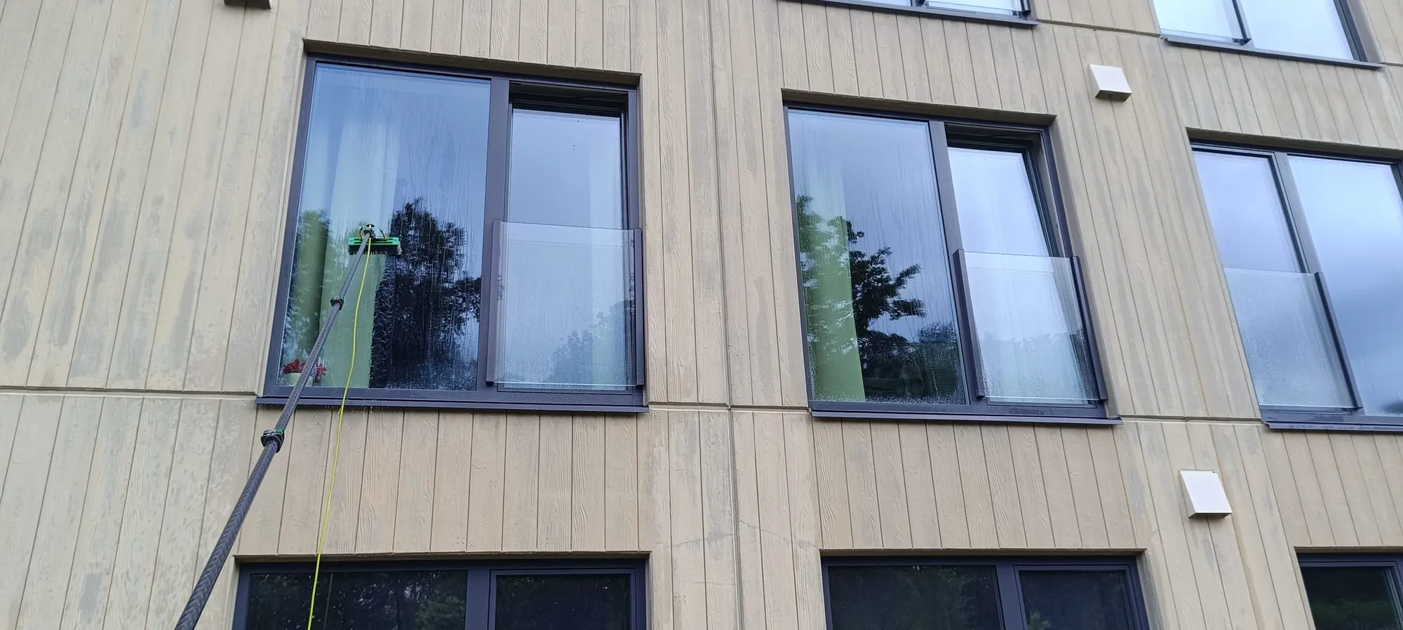 Teleskoophari pesemas korterelamu fassaadiakent, vesi voolab klaasil alla