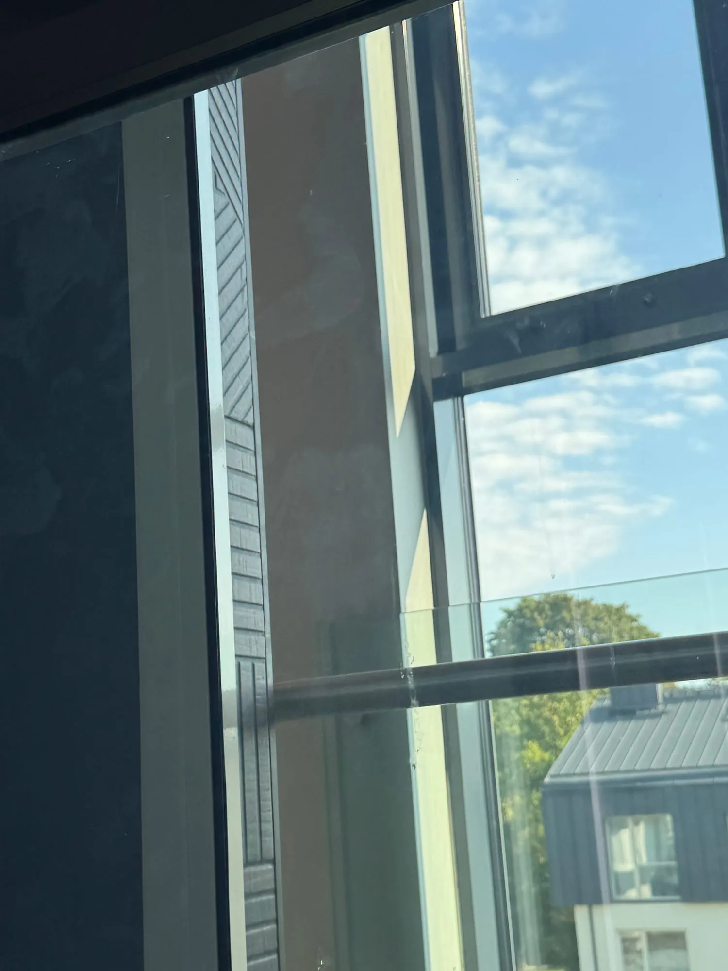 Läbi puhta liftišahti klaasi paistavad taevas, puu ja naaberhoone