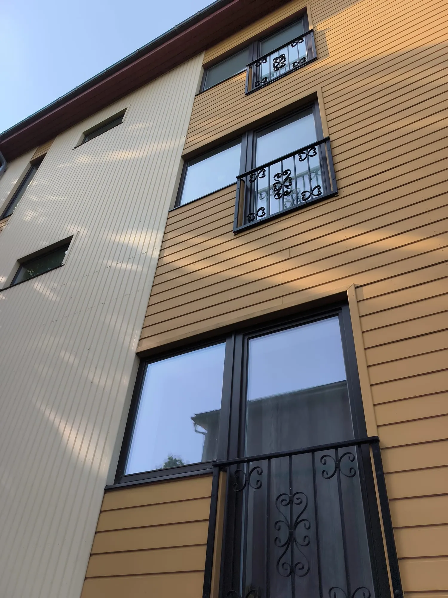 Korterelamu puhtaks pestud fassaadiaknad peegeldamas selget taevast