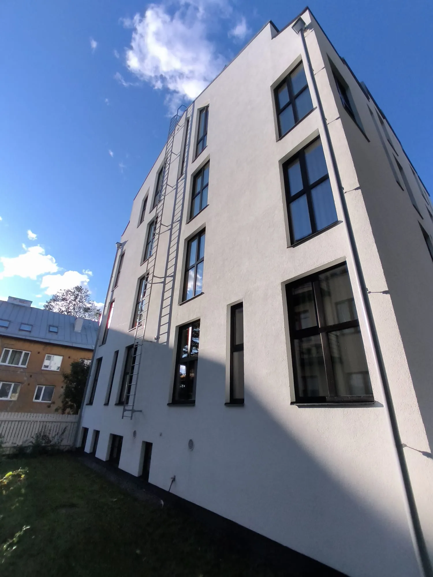 Kortermaja nurgavaade alt üles puhastatud fassaadiakendega