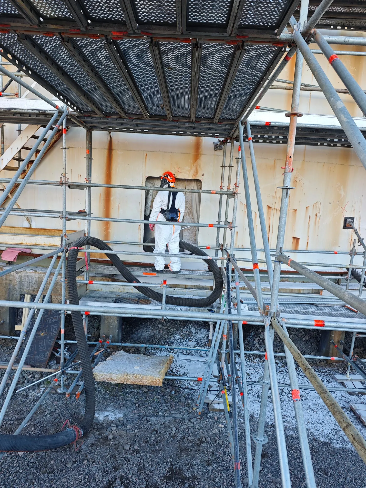 Tehnik kaitseülikonnas ja täismaskiga sisenemas etüleenimahutisse tellingute vahelt kinnise ruumi (confined space) töödeks