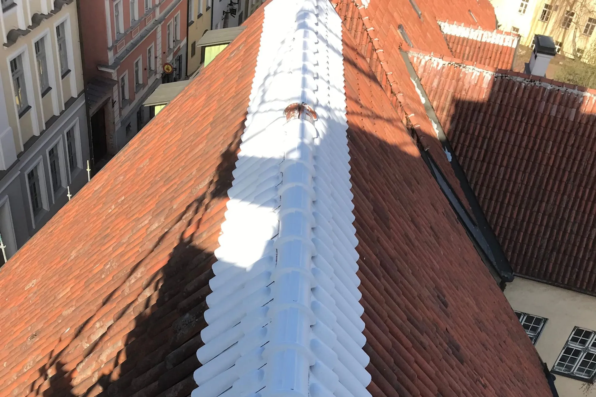Valgeks värvitud katusehari kulgeb mööda Pühavaimu kiriku punast kivikatust, all vanalinna tänav.