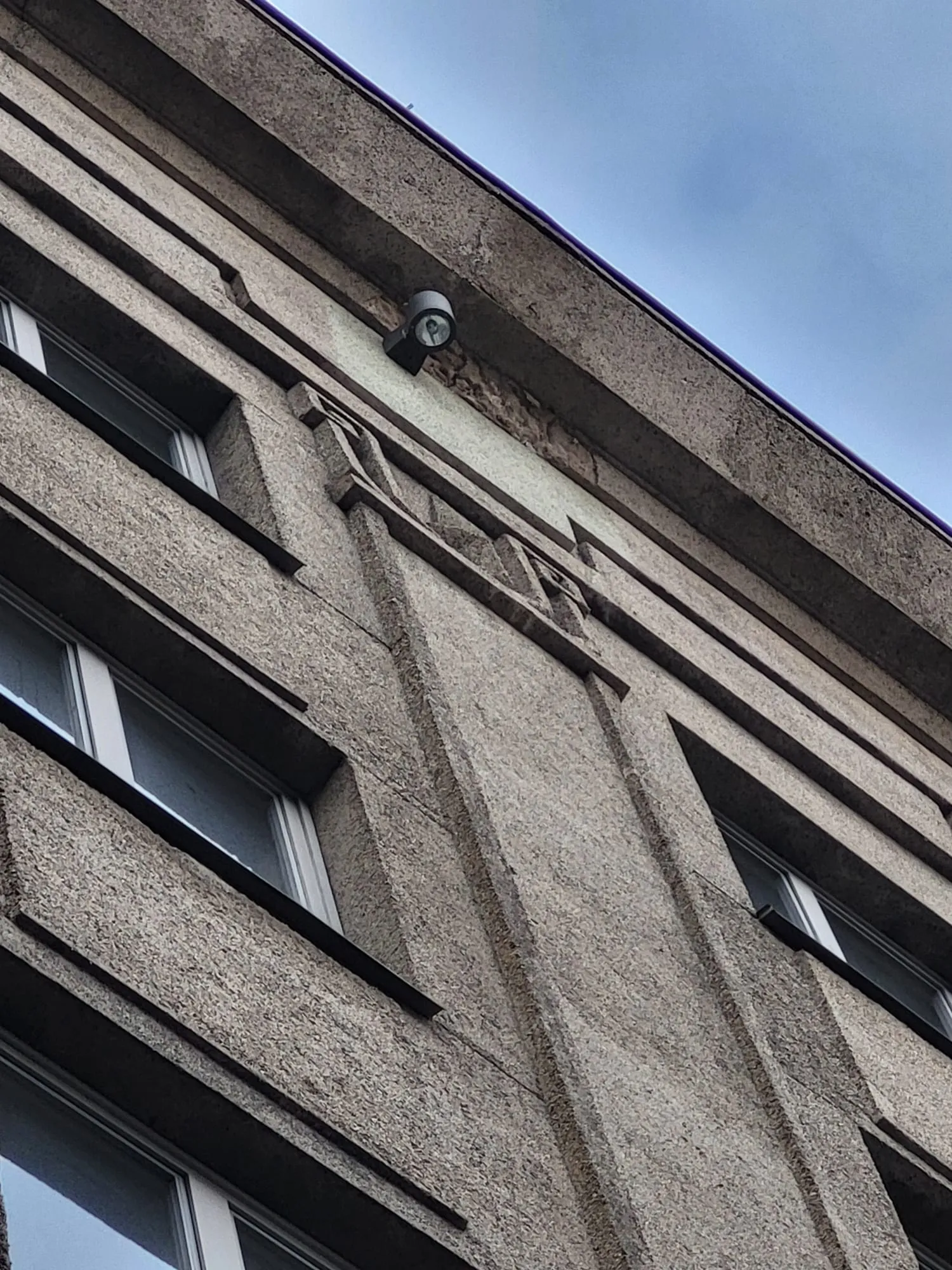 Hotellihoone kõrge fassaad, kus katuse all paistab pragunenud ja lahti tulnud fassaadikrohv