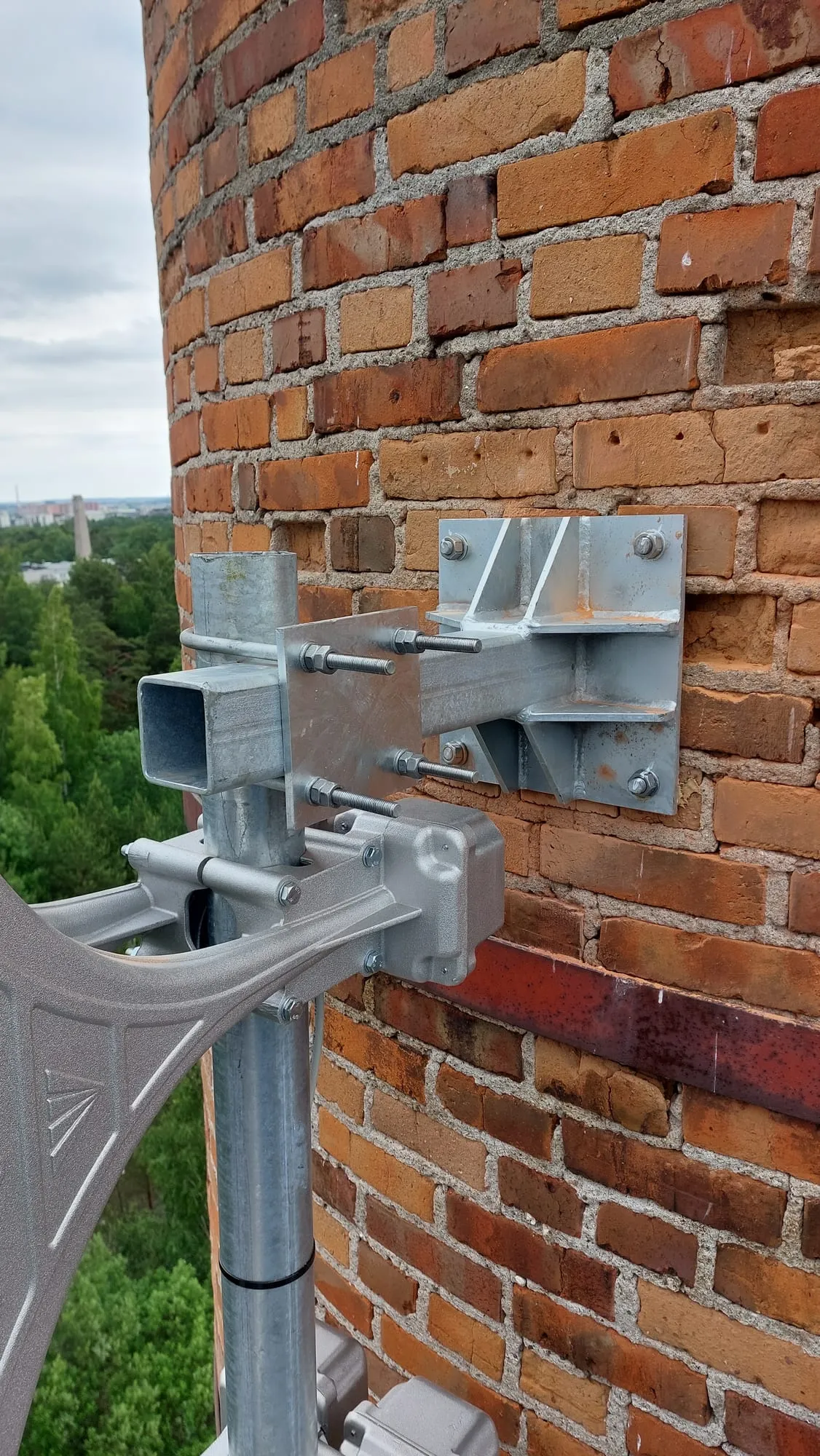 Sireenide kandemasti kinnitus telliskorstna küljes, taustal metsane maastik