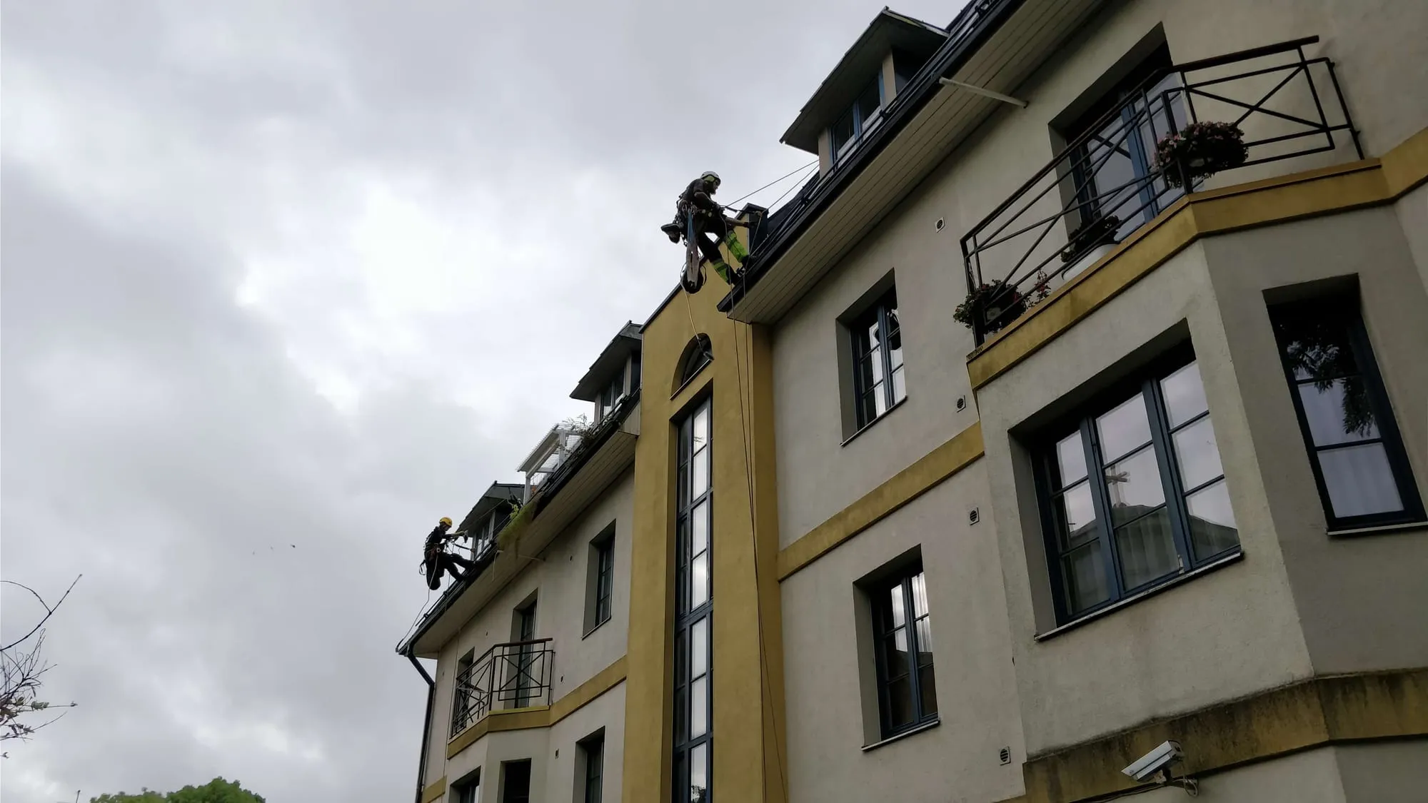 Köistehnik laskub köiel mööda hoone fassaadi vihmaveerennide juurde