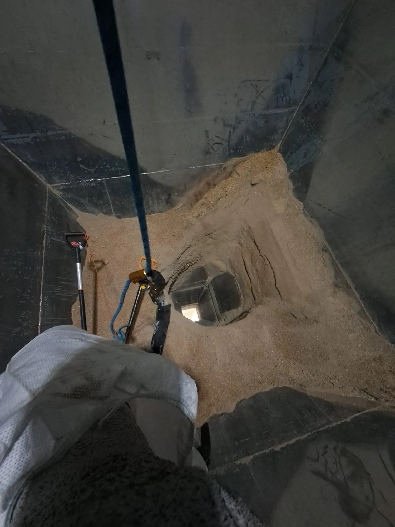 Köistehnik turvaköiel silo koonuses, all paistab tühjendusava ja tööriistad viljakihil
