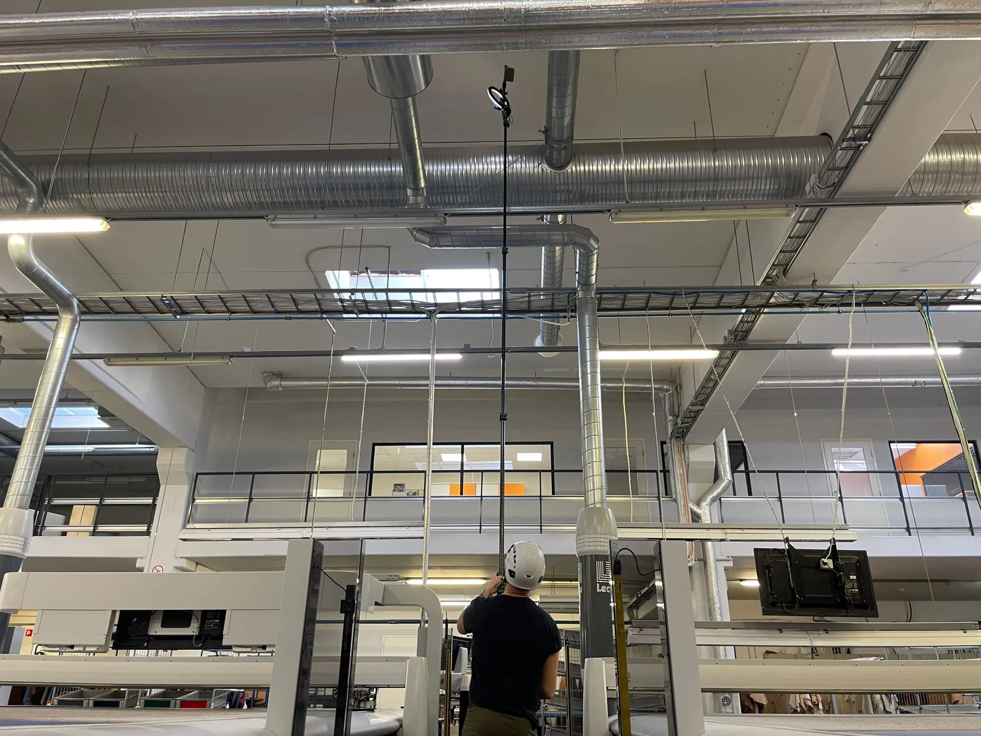 Tehnik uurib teleskoopvardaga tootmishoone lae ventilatsioonitorusid tolmuauditi käigus
