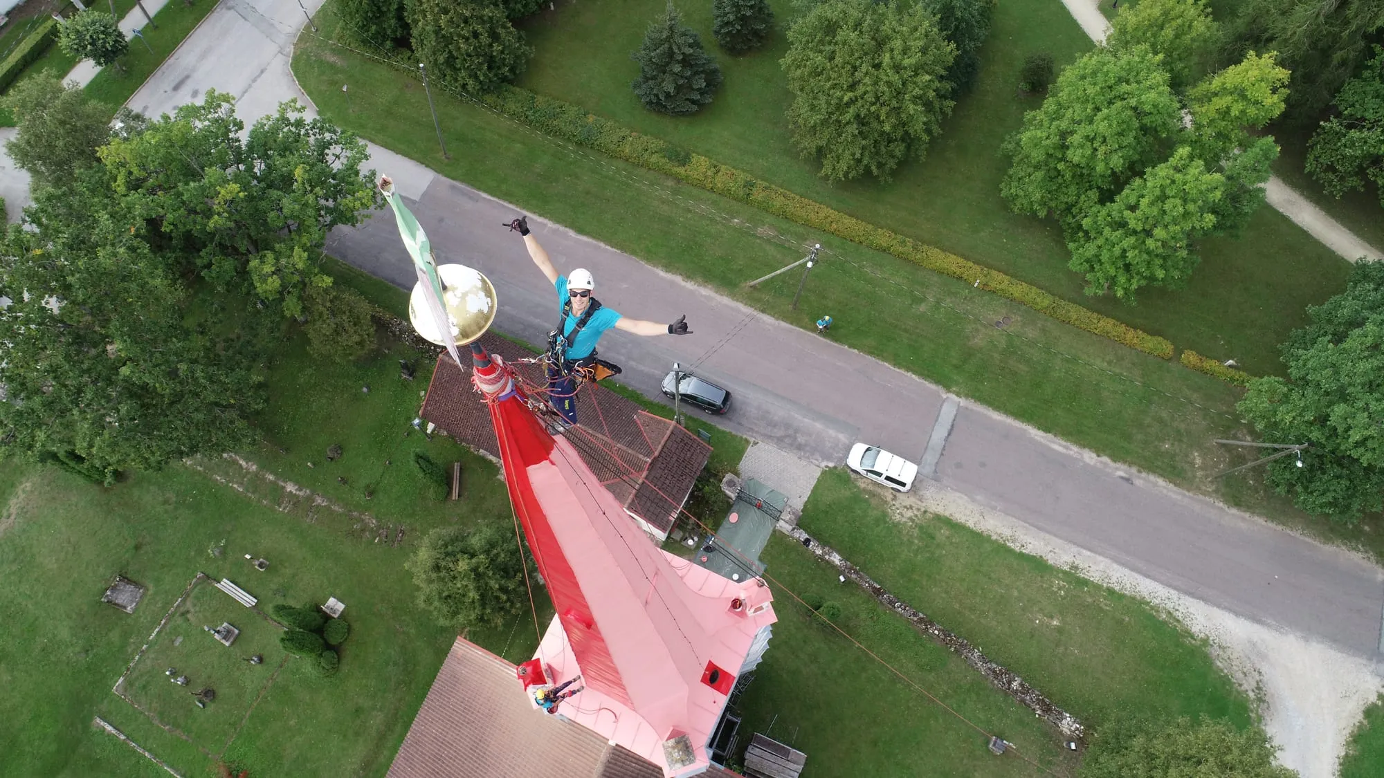 Ülaltvaade torni tipust — köietehnik kiivris ja rakmetes kuldse torniõuna kõrval, all kirik ja tänav